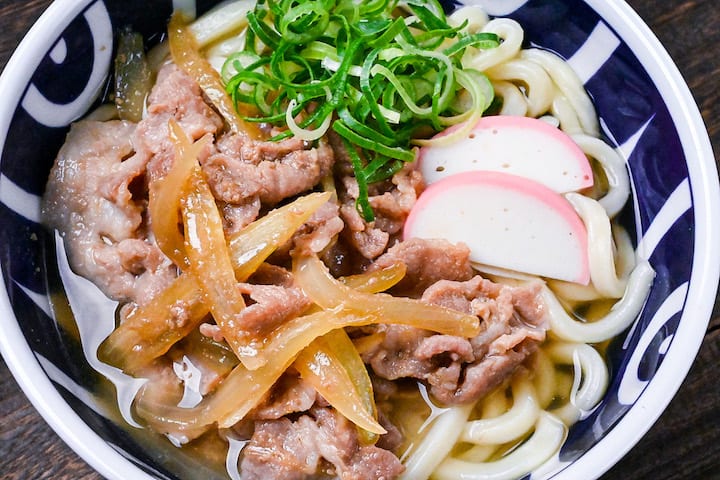 Pork udon noodle soup with pork belly, onions and kamaboko