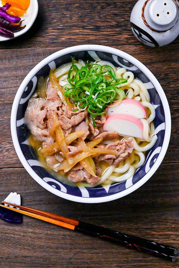 Pork udon noodle soup with pork belly, onions and kamaboko