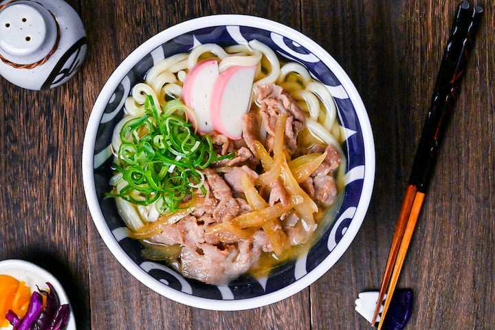 Pork udon noodle soup with pork belly, onions and kamaboko