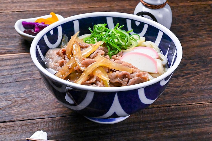 Pork udon noodle soup with pork belly, onions and kamaboko