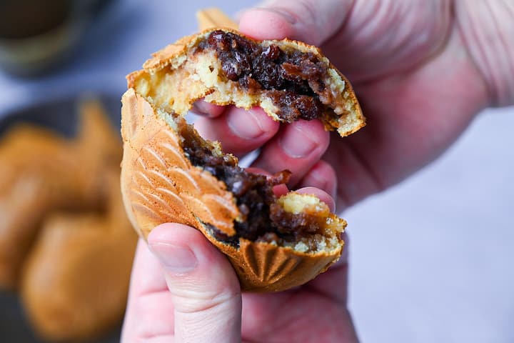 A Taiyaki cake ripped in half to reveal red bean filling