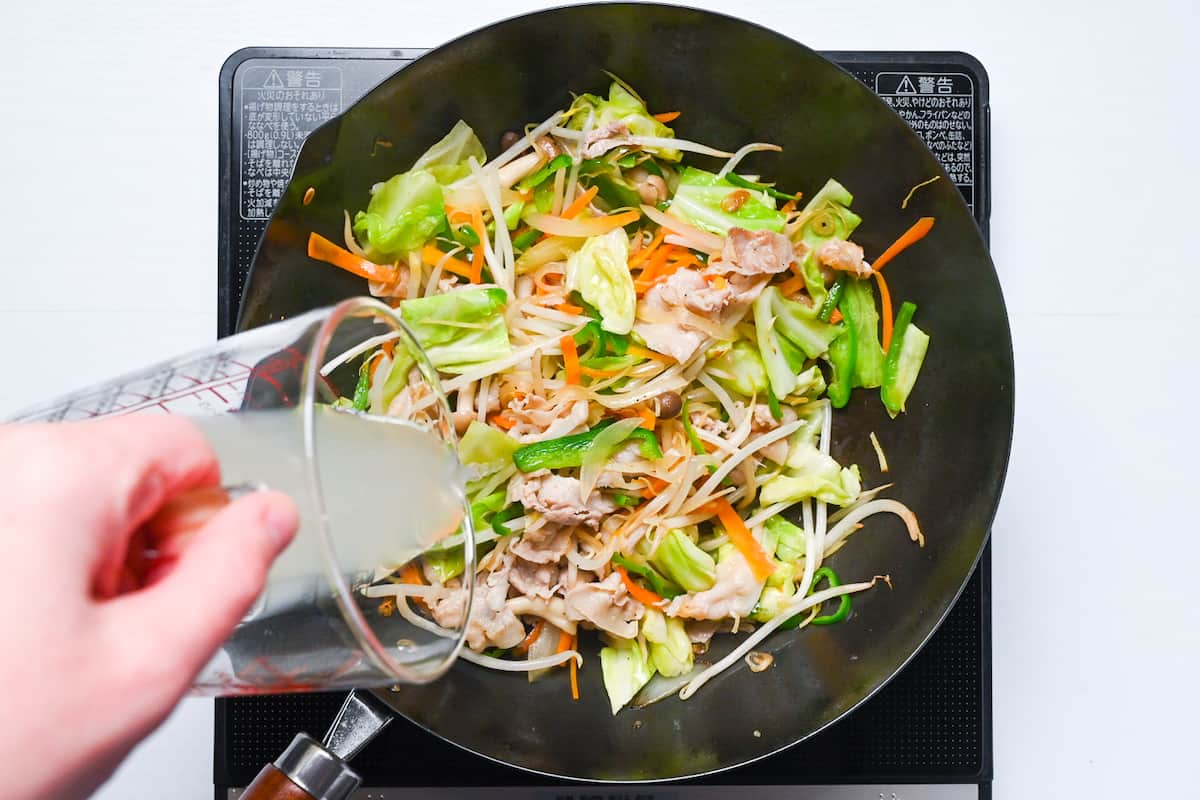 adding chicken stock and seasonings to yasai itame