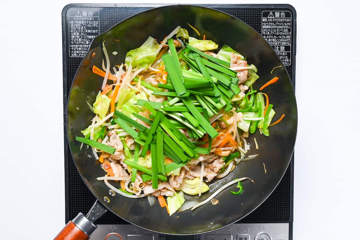 adding chives to the wok