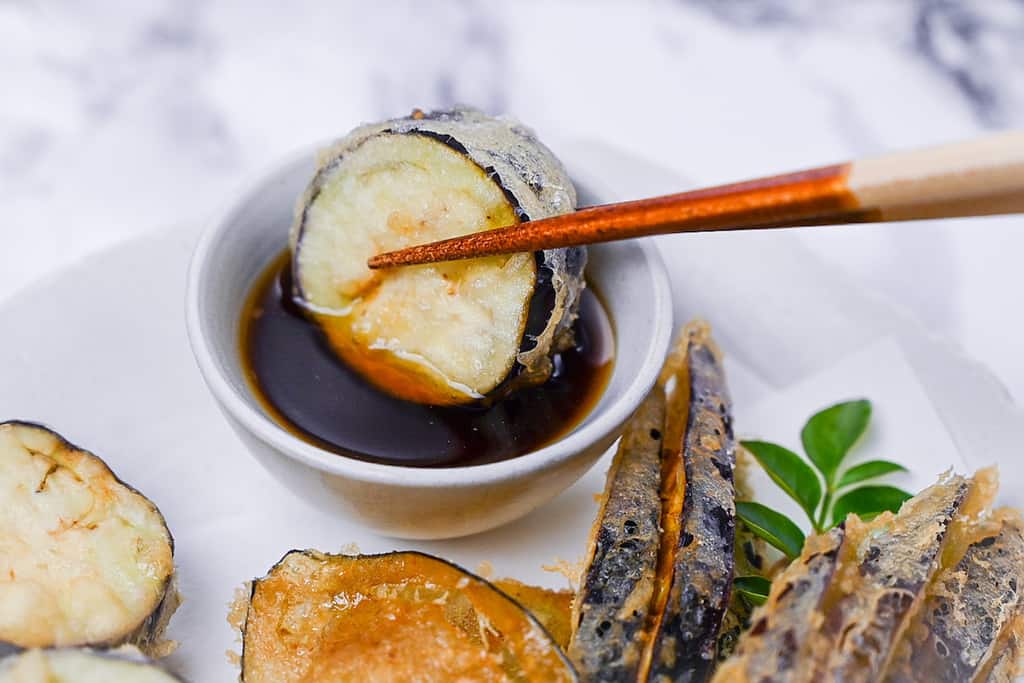 Dipping round eggplant tempura in tentsuyu