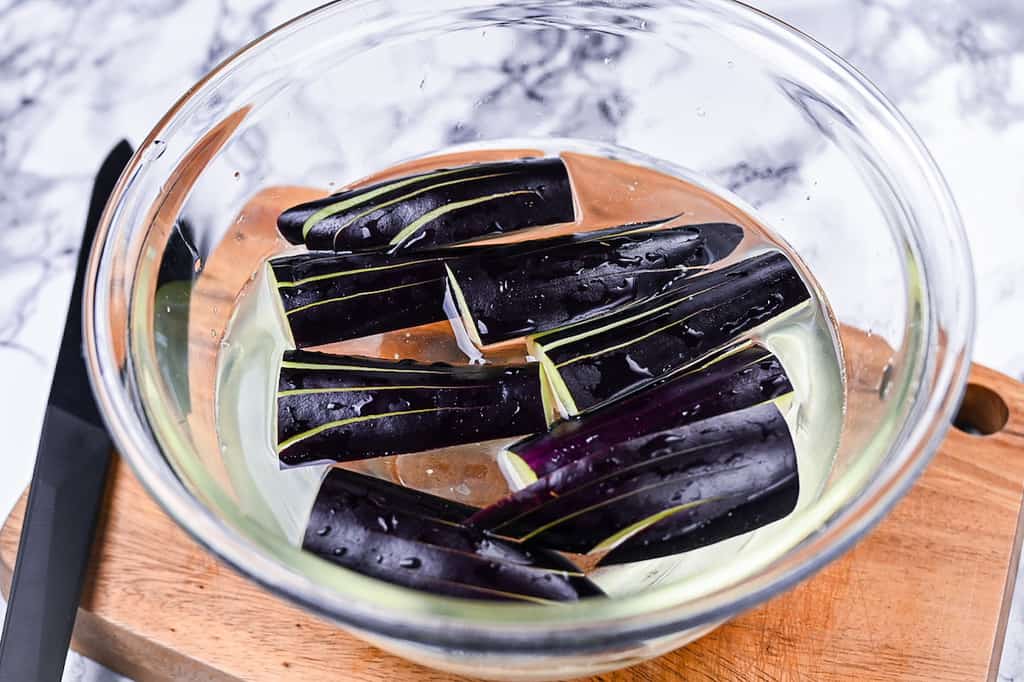 Suehiro cut eggplant soaking in a bowl of salt water