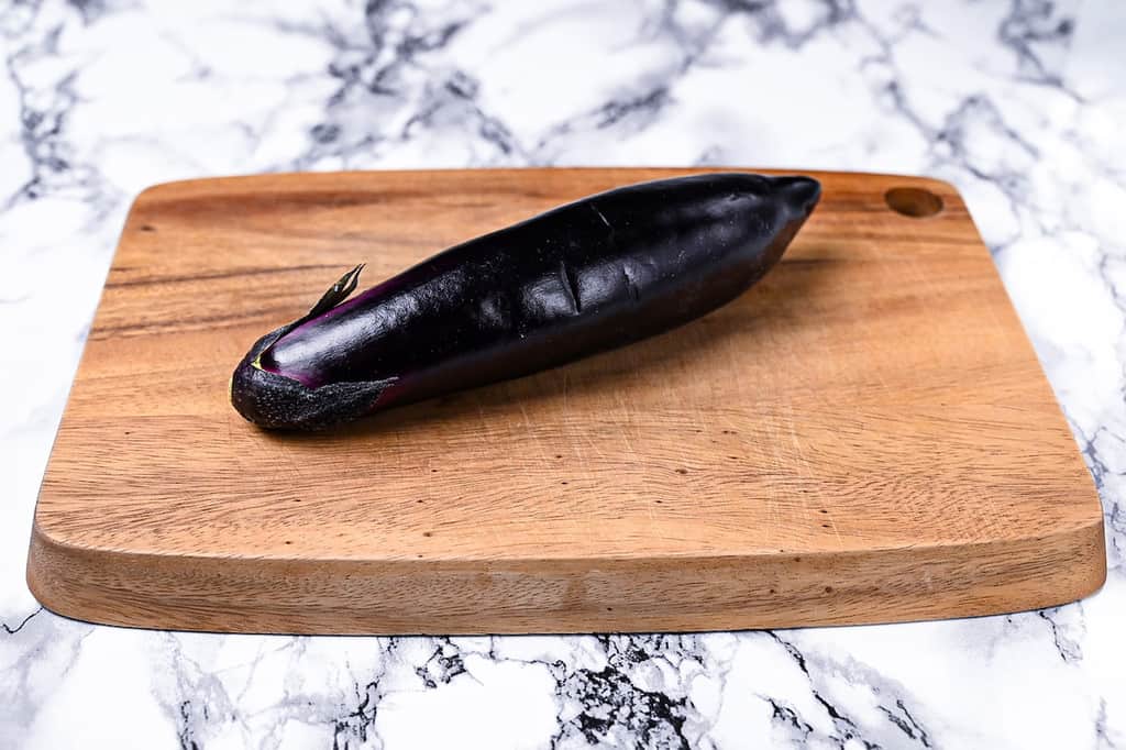 A Japanese eggplant on a wooden chopping board