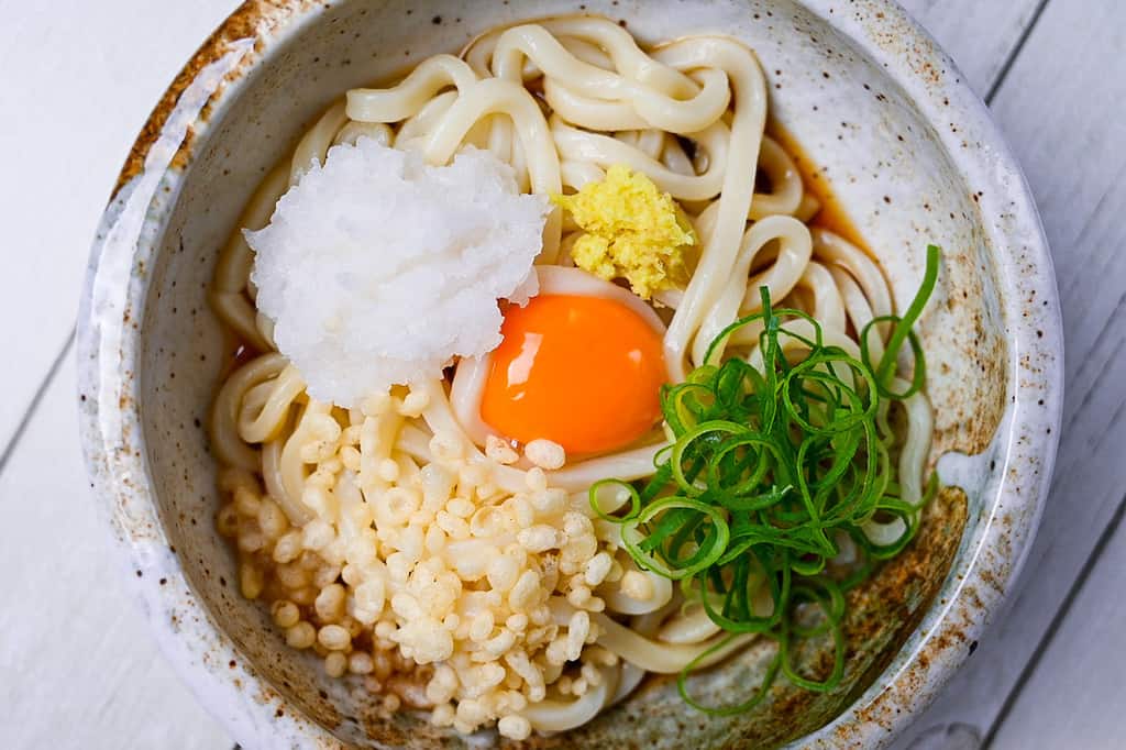 Bukakke udon noodles in a rich broth topped with egg yolk and a variety of refreshing toppings