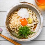 Bukkake udon noodles in a rich broth topped with egg yolk and a variety of refreshing toppings