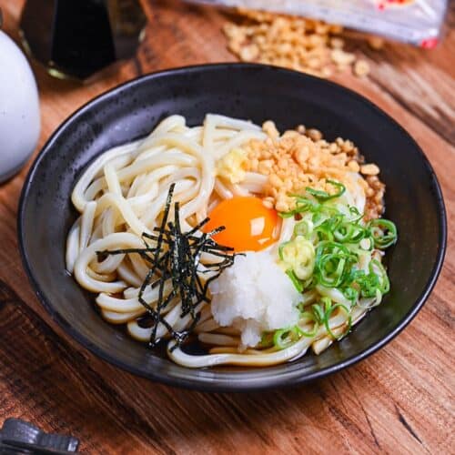 lifting mixed bukkake udon with black chopsticks