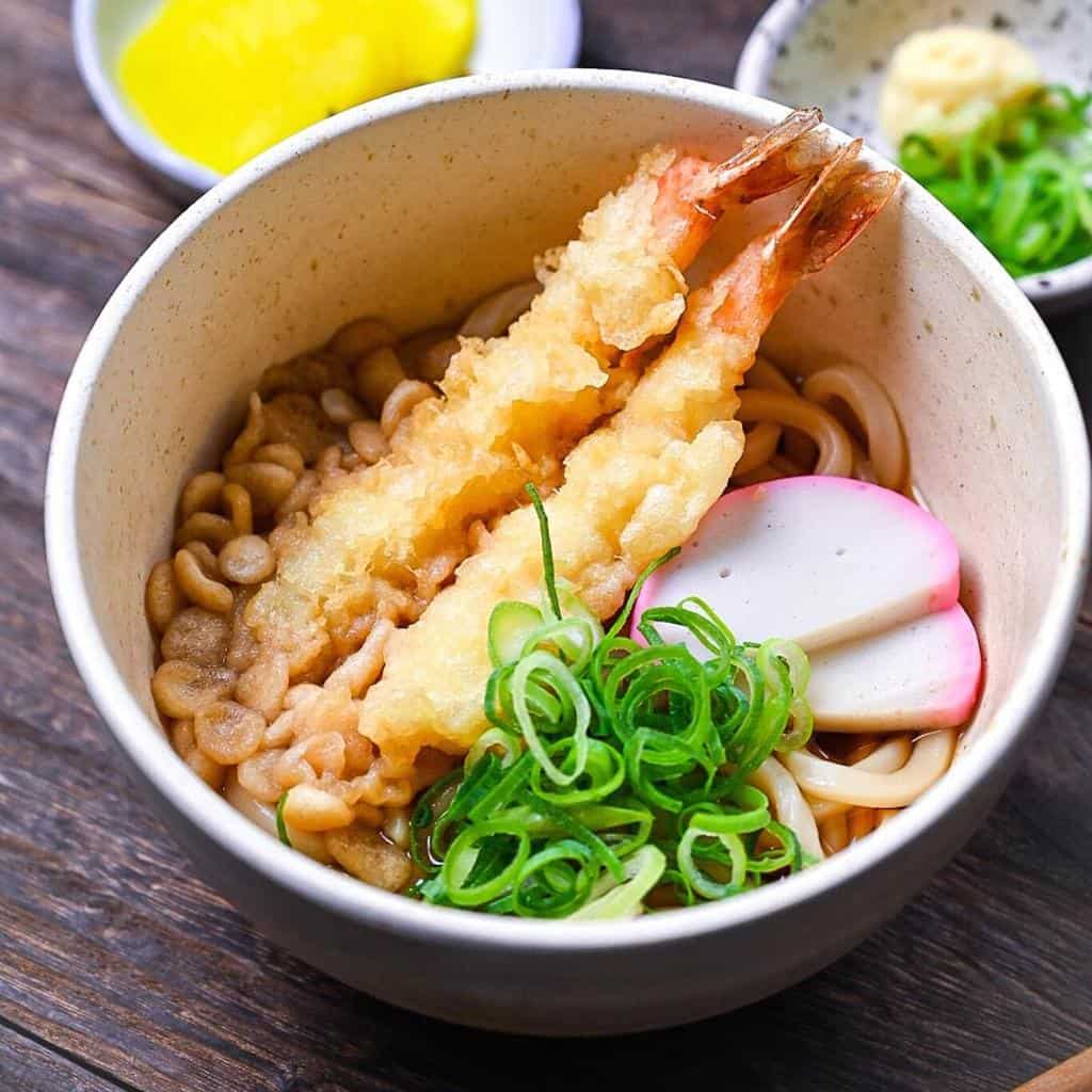 Ebiten udon served in a cream bowl with spring onion, grated ginger and pickles on the side featured img