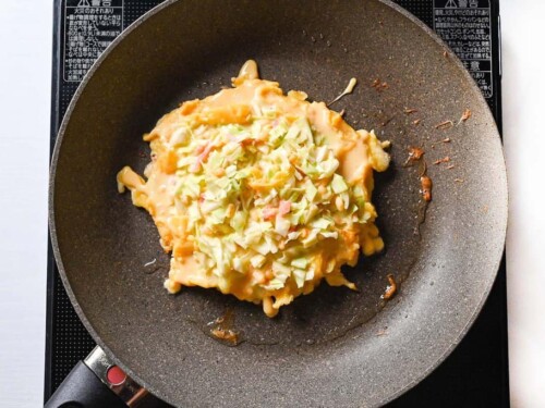 Adding okonomiyaki batter to preheated pan