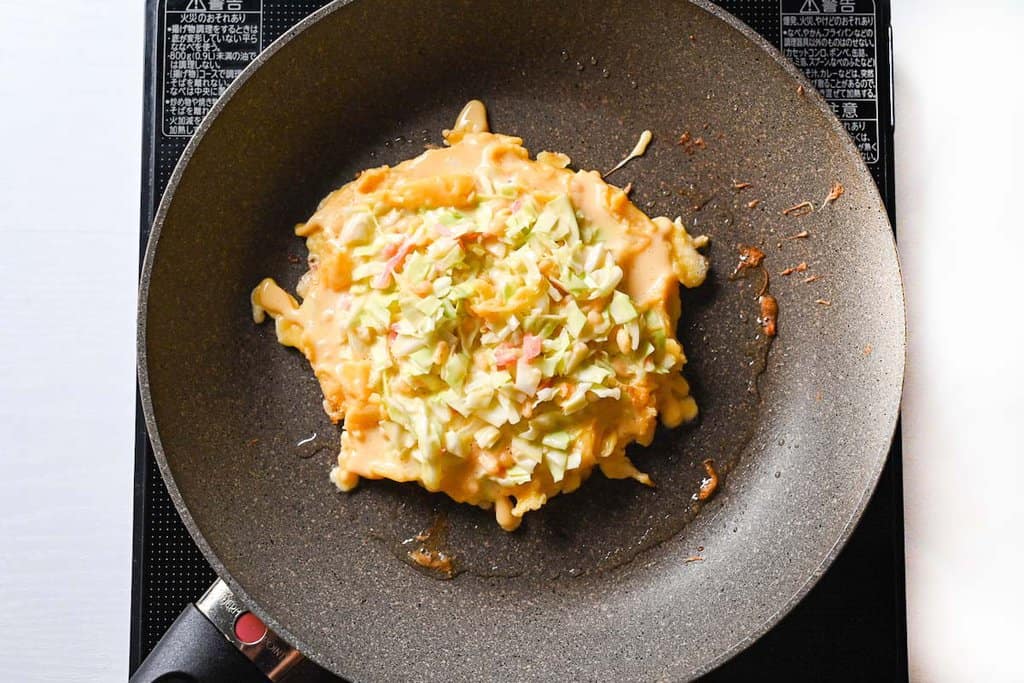 Adding okonomiyaki batter to preheated pan