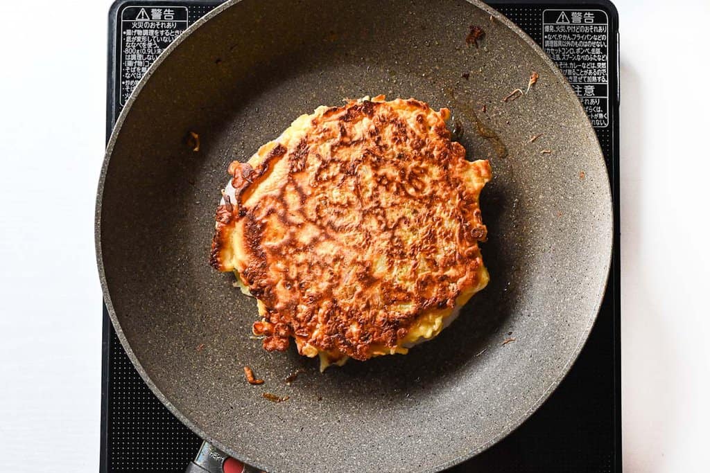 flipping okonomiyaki in a frying pan