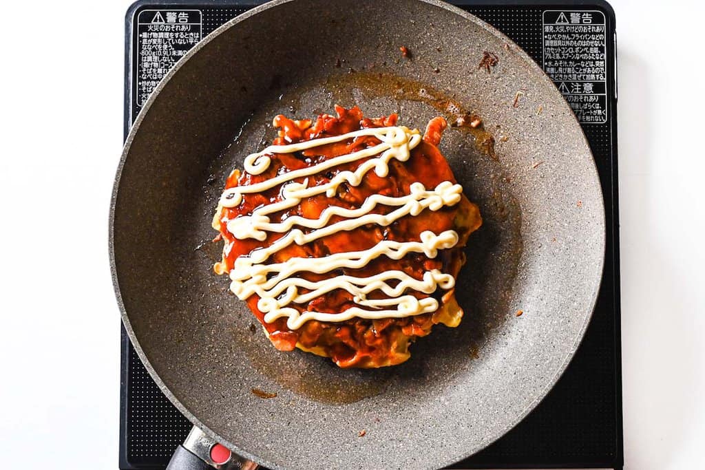 Drizzling okonomiyaki with Japanese mayonnaise