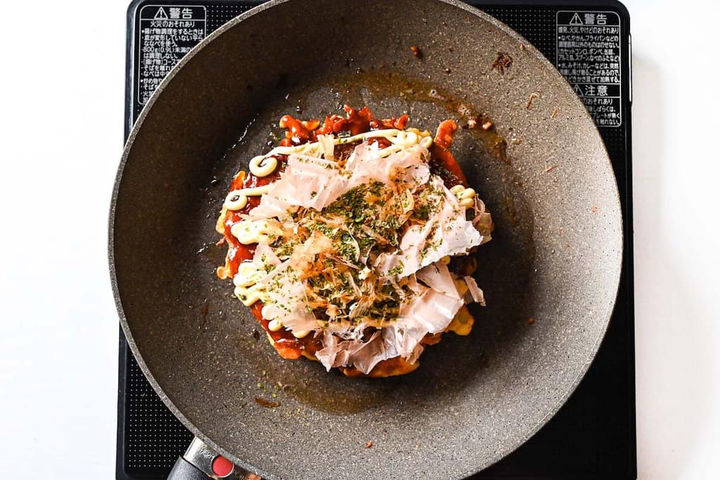 Topping okonomiyaki with bonito flakes and seaweed powder