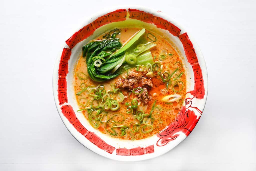 topping tantanmen with pak choi and spring onions