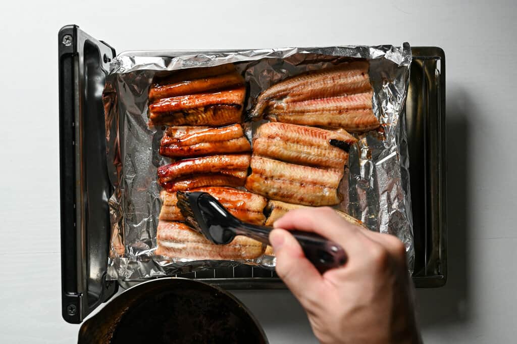 applying unagi sauce on meat side on a grill