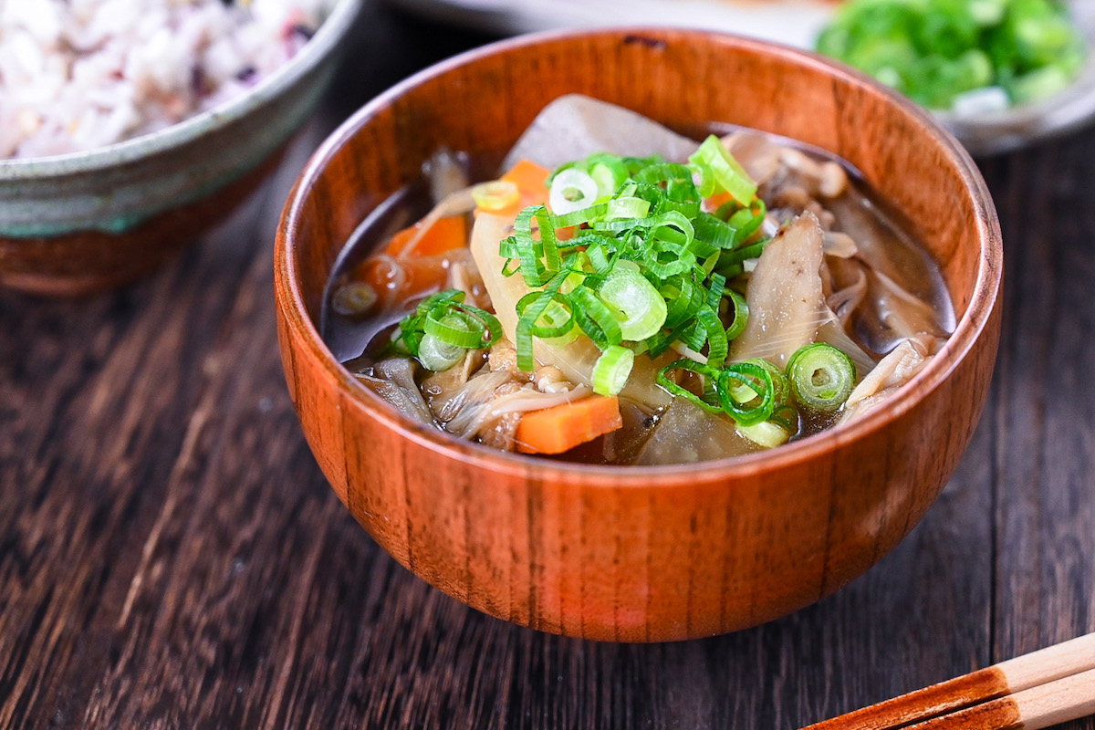 Japanese vegetable soup "kenchin jiru" served in a wooden bowl and topped with chopped spring onions