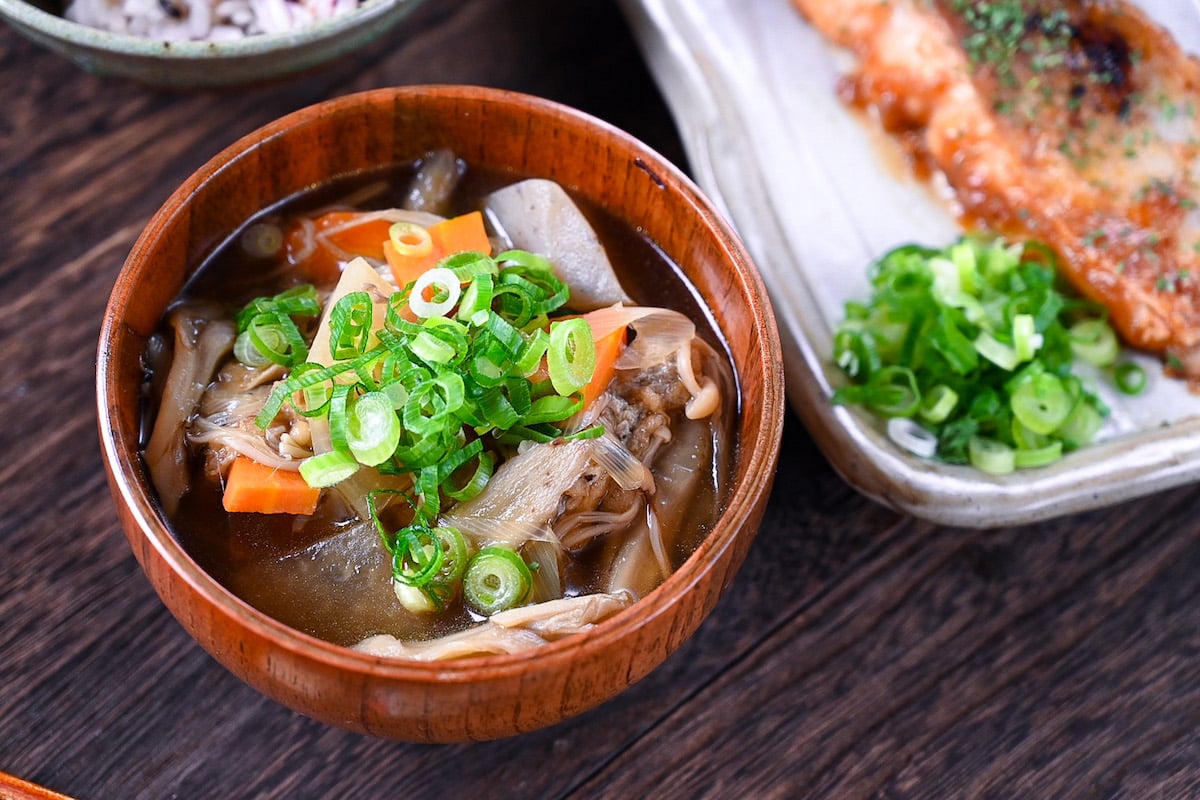 Japanese vegetable soup "kenchin jiru" served in a wooden bowl and topped with chopped spring onions