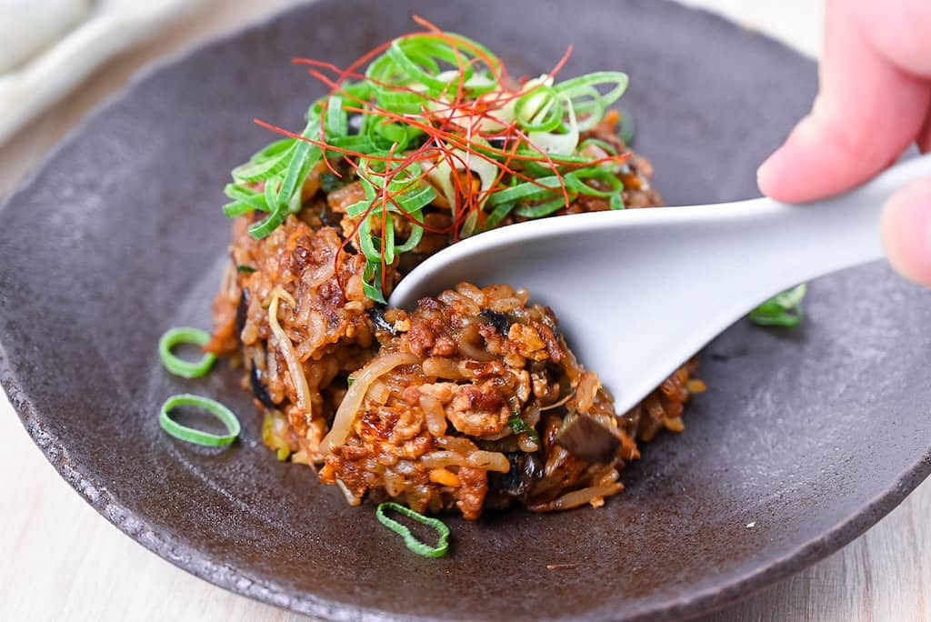 Taking a scoop of pork and miso yakimeshi fried rice with light grey ceramic spoon