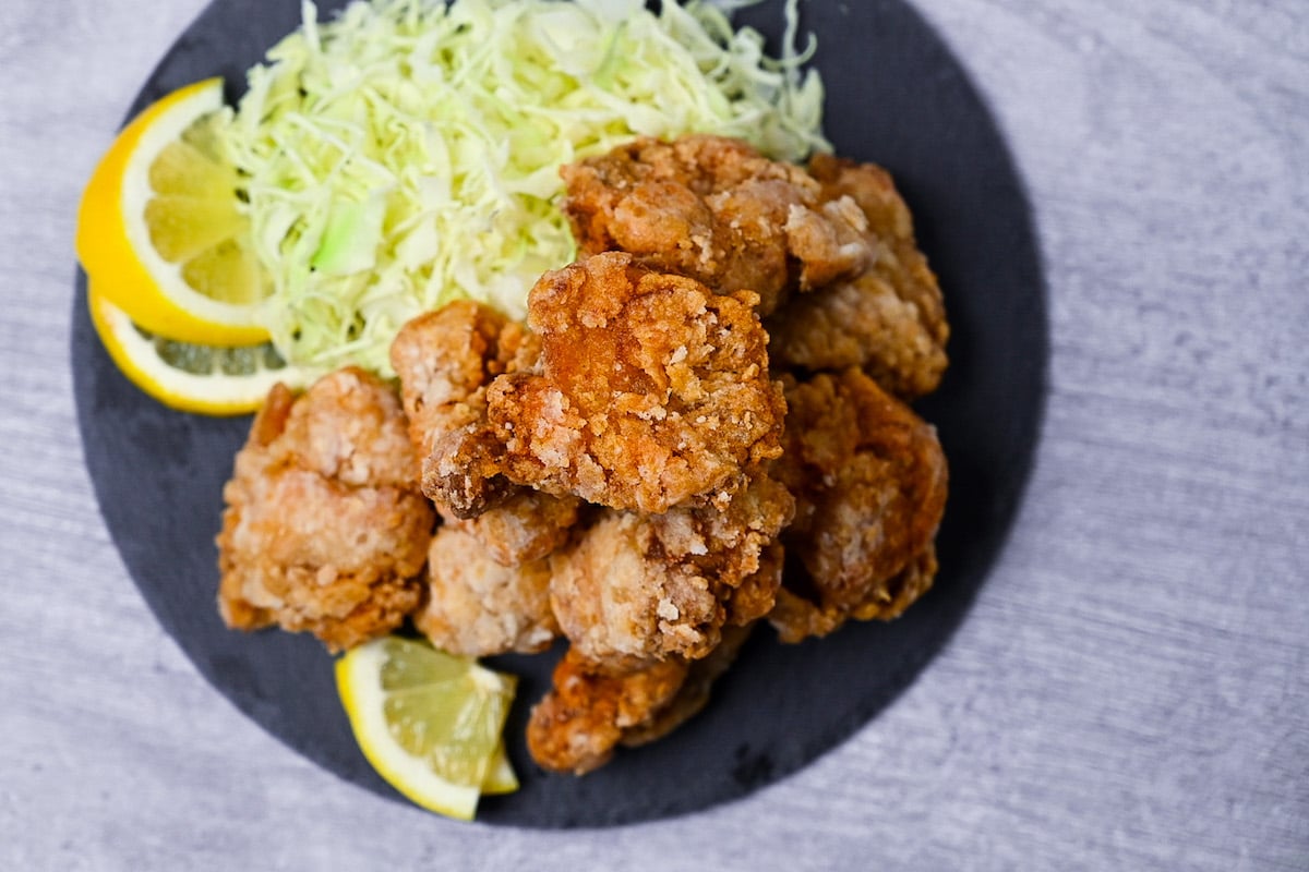 Japanese chicken tatsuta age served on a slate slate with cabbage and lemon