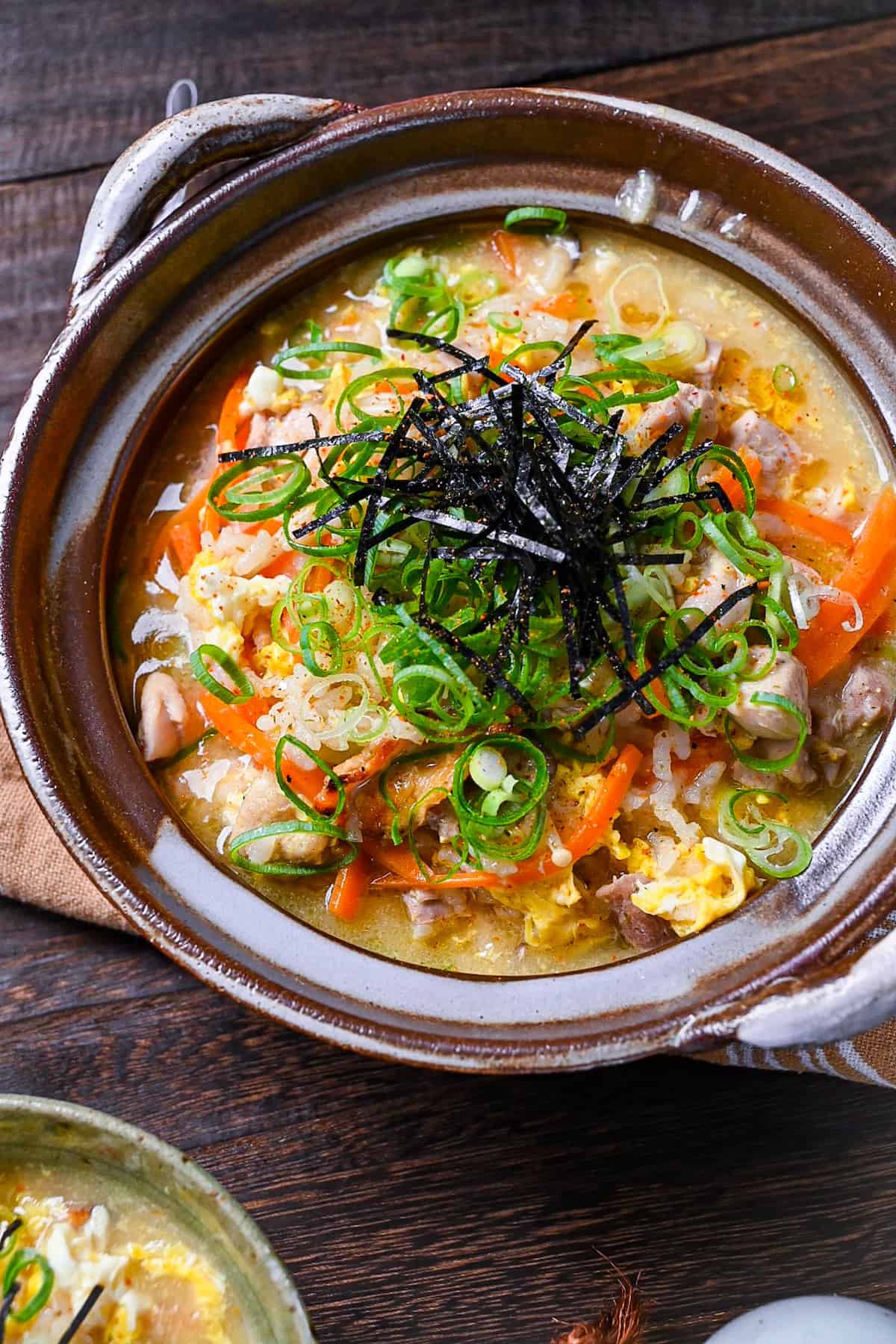 Japanese chicken rice soup (zosui / ojiya) in a brown nabe topped with kizami nori