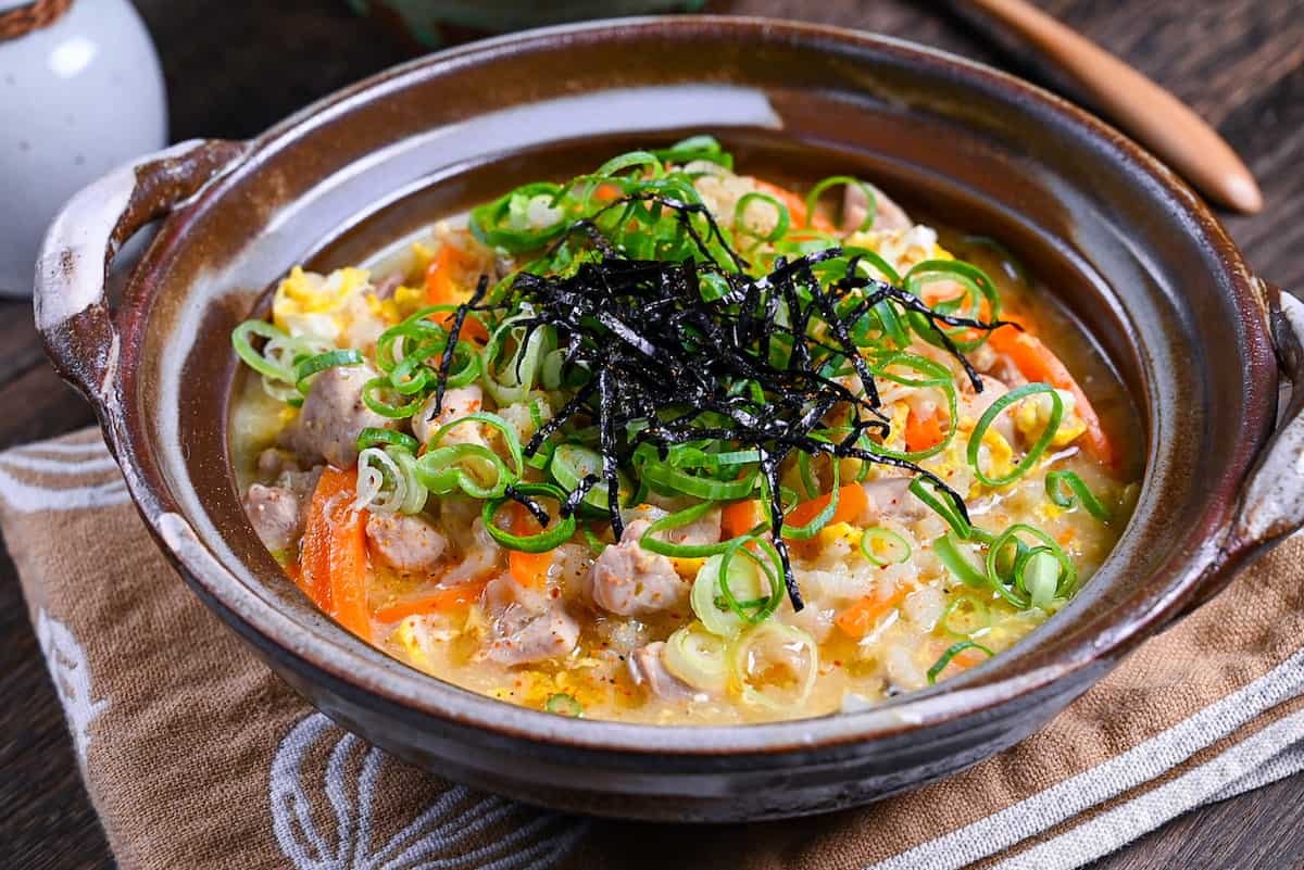 Japanese chicken rice soup (zosui / ojiya) in a brown nabe topped with kizami nori