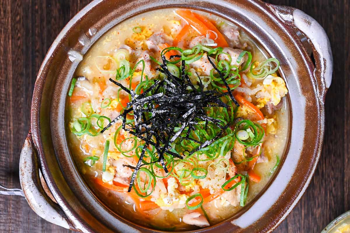 Japanese chicken rice soup (zosui / ojiya) in a brown nabe topped with kizami nori