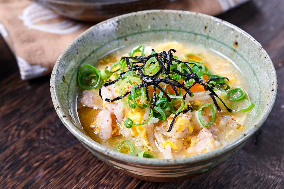 Japanese chicken rice soup (zosui / ojiya) in a green mottled rice bowl topped with kizami nori