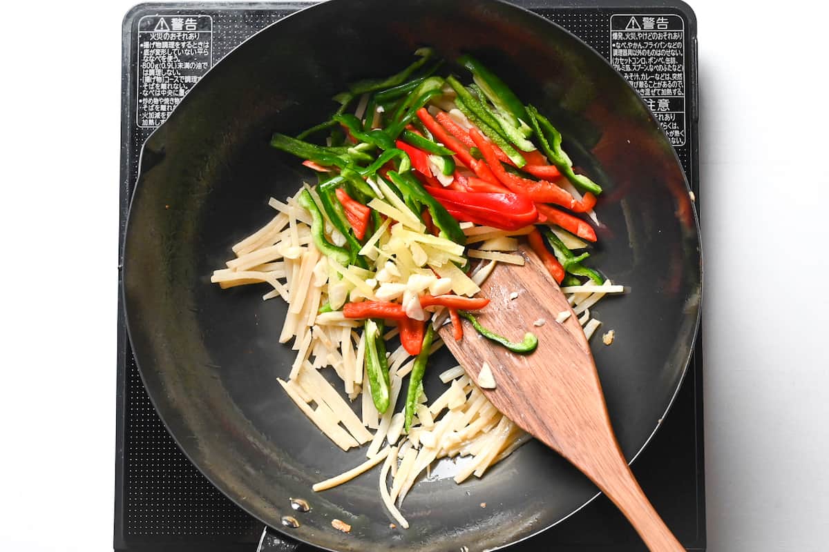 frying red and green bell peppers in wok for chinjao rosu