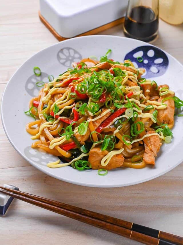 Chicken yaki udon served on a white plate, drizzled with Japanese mayo and topped with spring onions