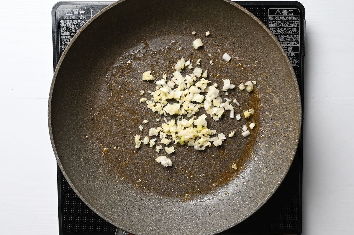 Frying finely diced spring onion, garlic and ginger in a pan