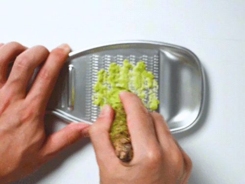 grating wasabi in a circular motion on a Japanese grater