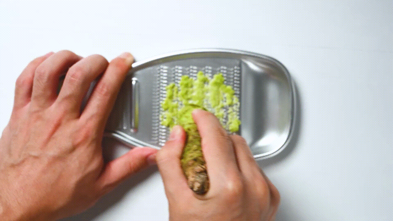 grating wasabi in a circular motion on a Japanese grater