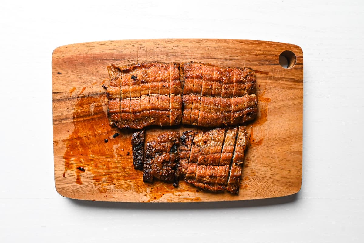 Grilled unagi (eel) cut into strips on a wooden chopping board