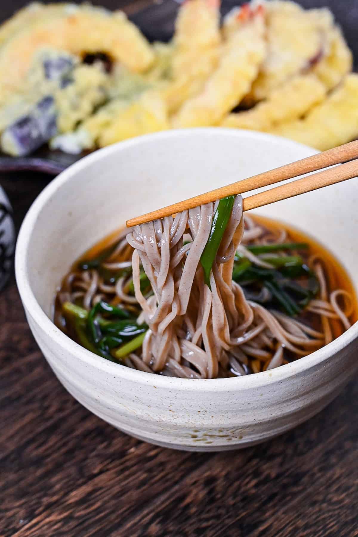 kake soba soup in a white bowl topped with spring onion