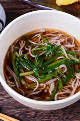 kake soba soup in a white bowl topped with spring onion