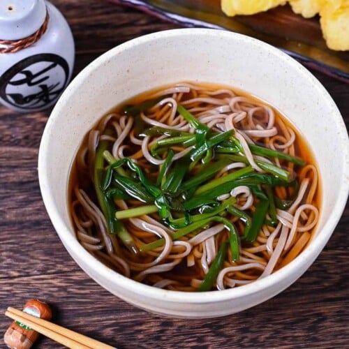 kake soba soup in a white bowl topped with spring onion