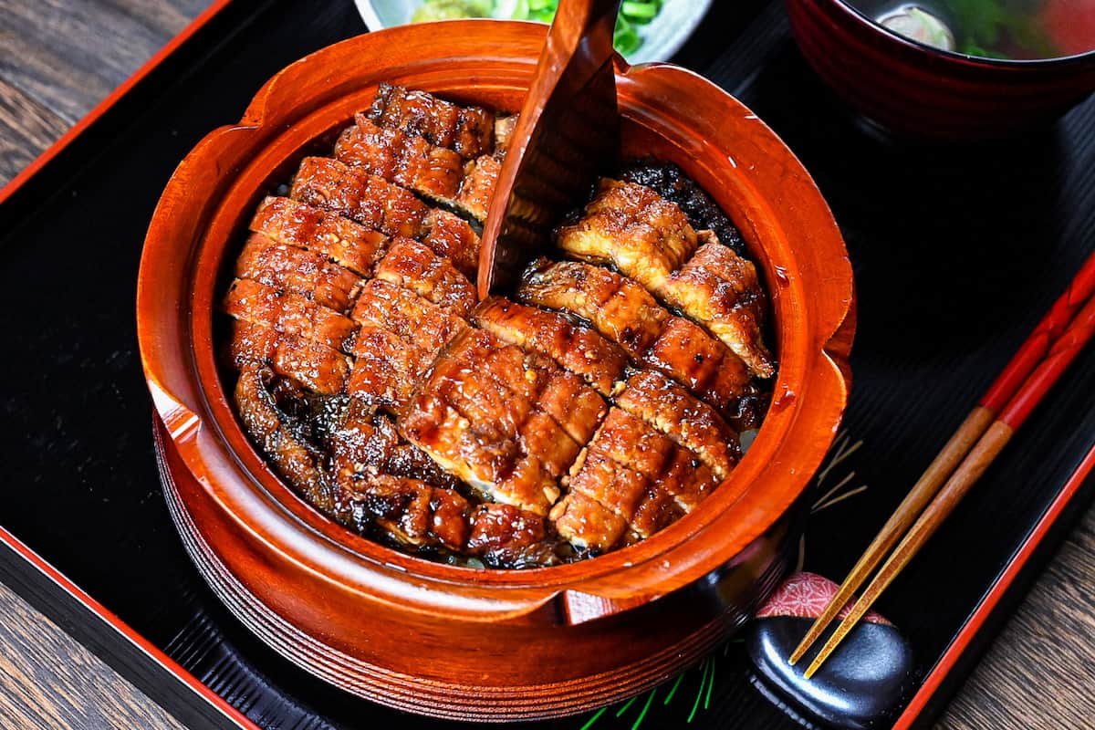 Dividing unagi hitsumabushi into quarters using a wooden rice paddle