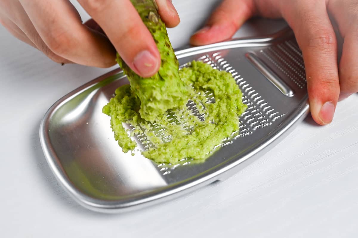 wasabi root being grated on a silver Japanese grater