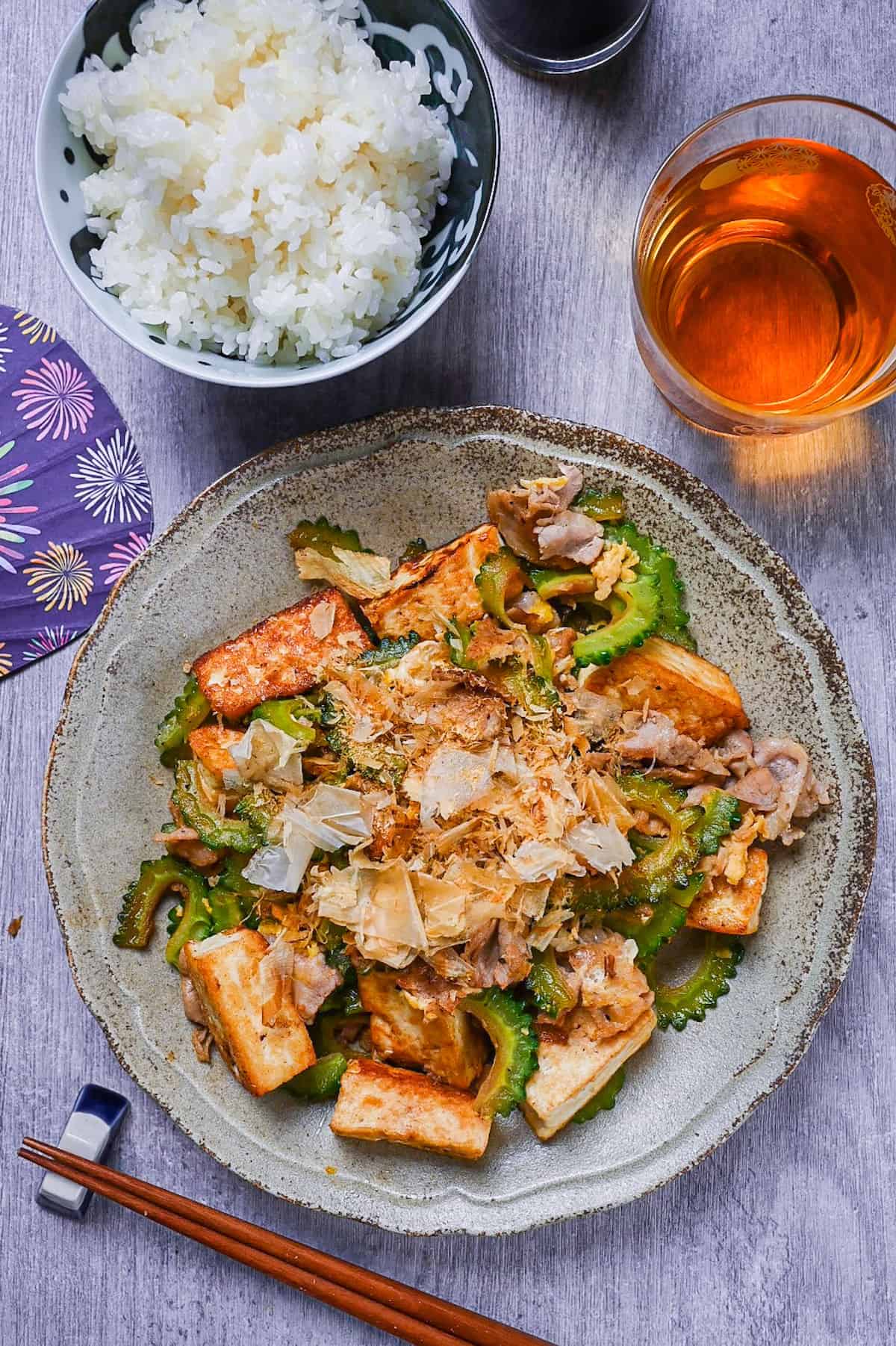 Goya Champuru (Okinawan Bitter Melon Stir Fry) on a grey plate with rice and iced tea top down view