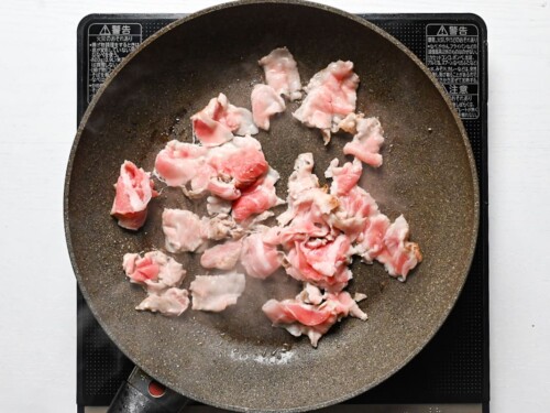 Thinly sliced pork belly cooking in a frying pan