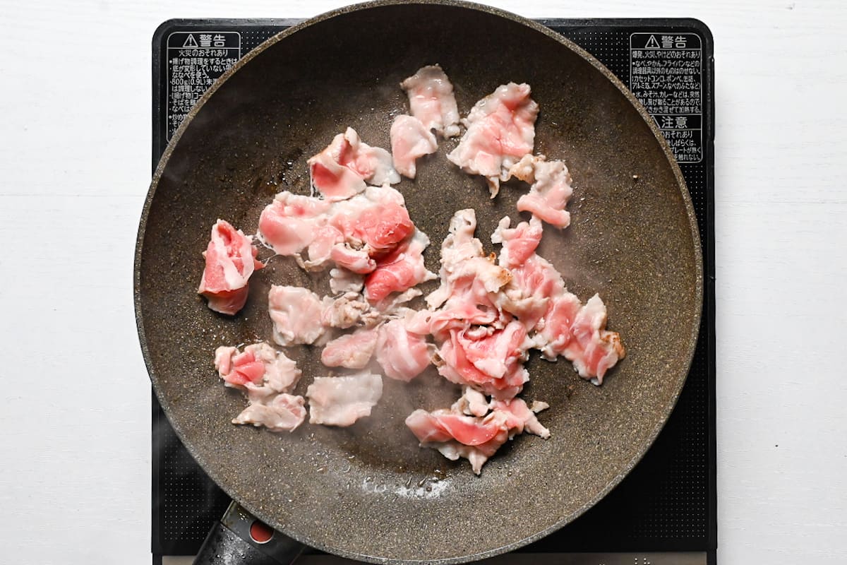 Thinly sliced pork belly cooking in a frying pan