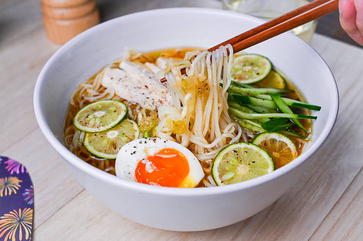 Chicken and citrus somen noodle soup in a white bowl with slices of sudachi