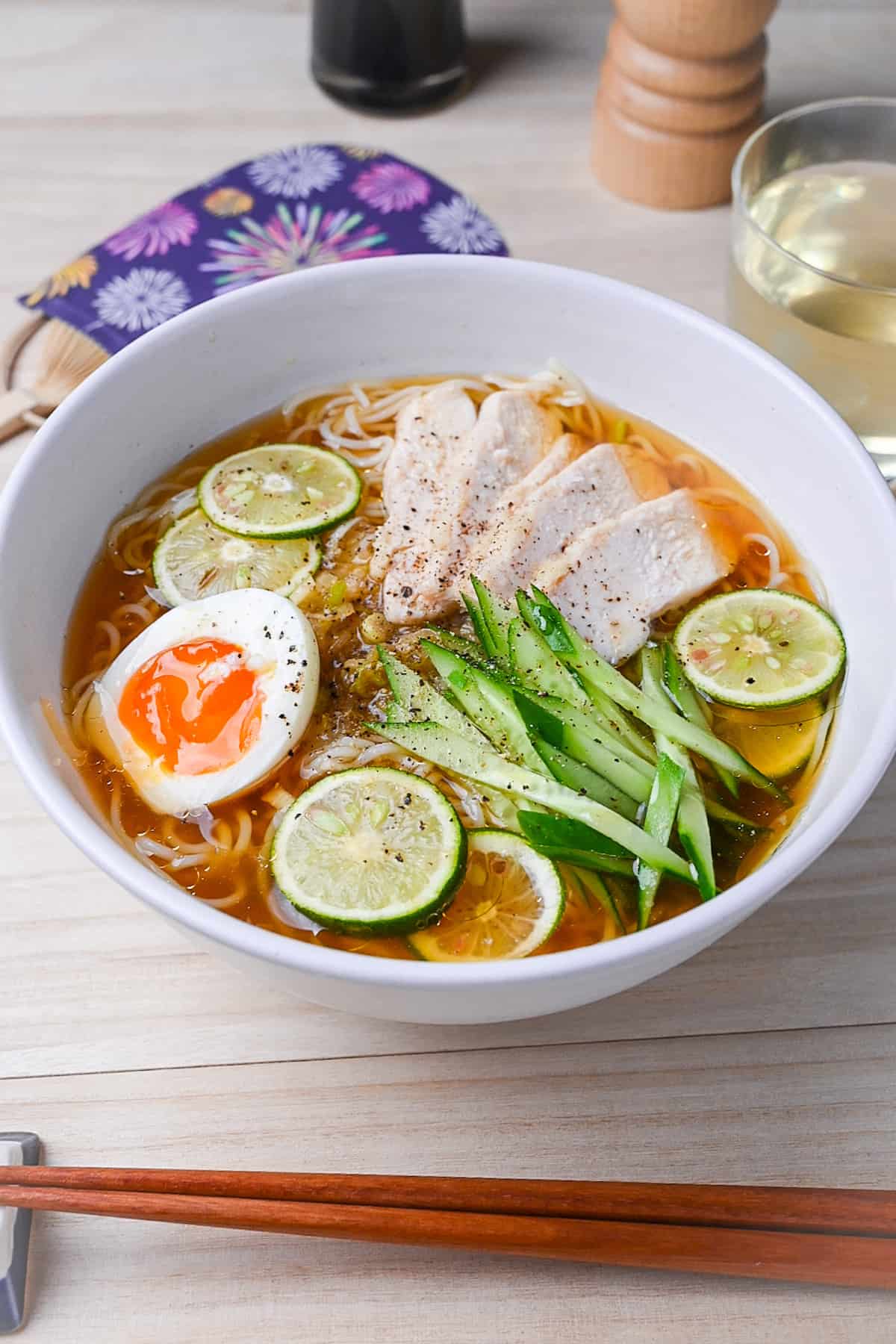 Chicken and citrus somen noodle soup in a white bowl with slices of sudachi