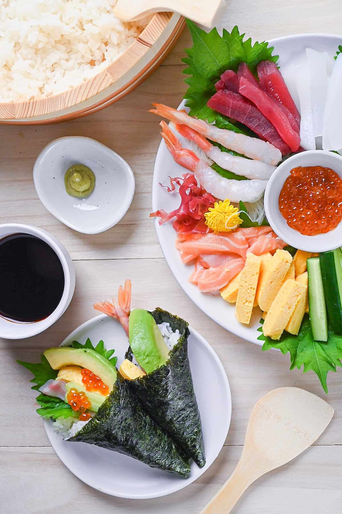 Japanese temaki sushi rolls with soy sauce, wasabi, sushi rice and an array of sliced sushi grade fish and fresh vegetables