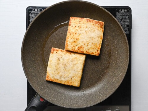 two pieces of firm tofu in a frying pan