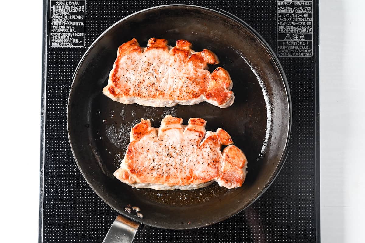 pork chops browned on top in frying pan