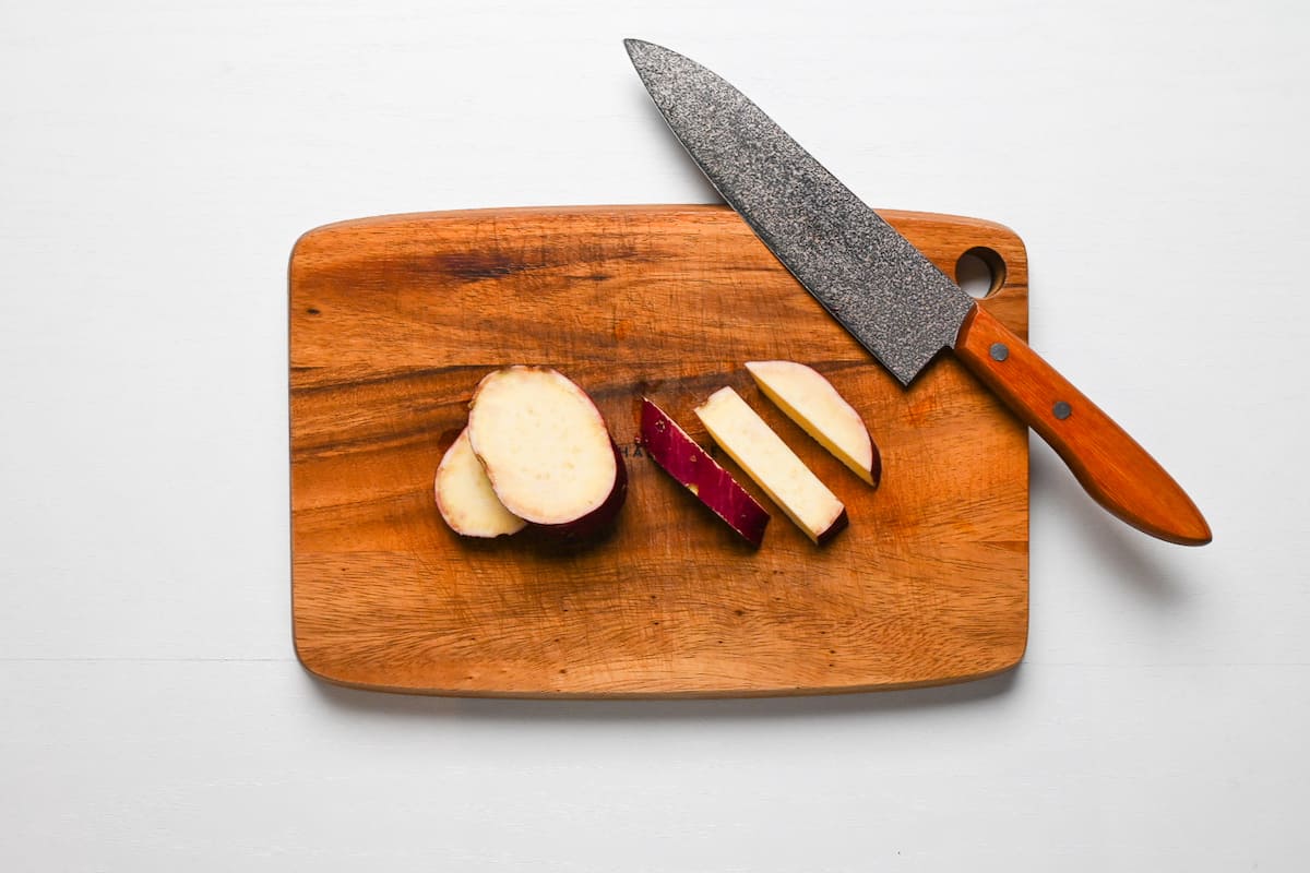 Japanese sweet potato cut into sticks on a wooden chopping board