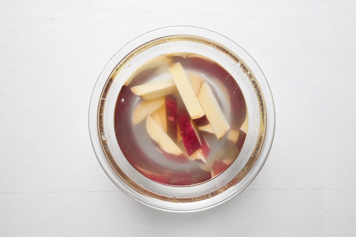 Pieces of Japanese sweet potato soaking in a glass bowl of water